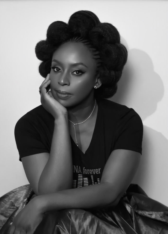 Portrait en noir et blanc d'une femme noire assise, la main gauche lui tenant le visage